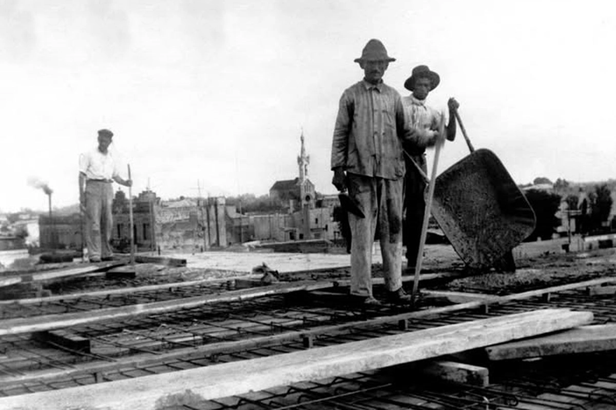 Trabajadores en el techo de lo que sería el municipio, con la iglesia Capuchinos en el horizonte. Trabajadores en el techo de lo que sería el municipio, con la iglesia Capuchinos en el horizonte.