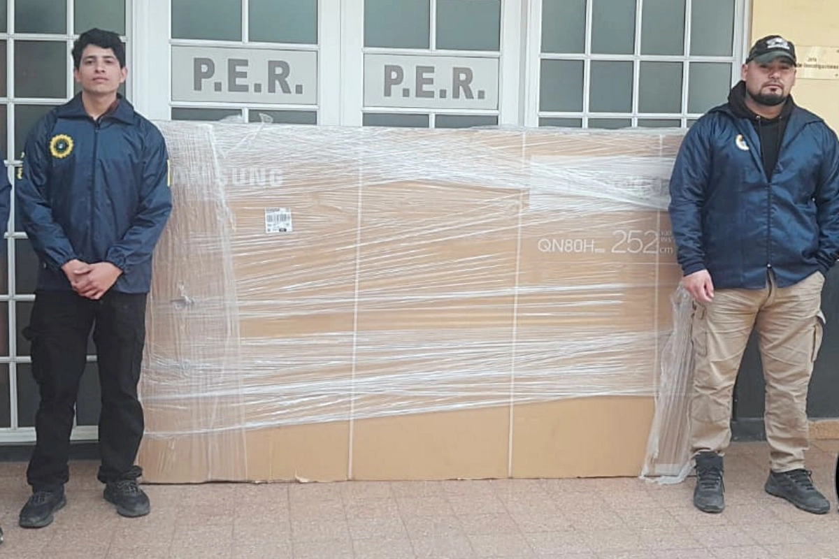 Los efectivos policiales con el televisor incautado.